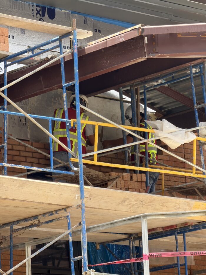 Construction workers laying bricks by the school skybridge