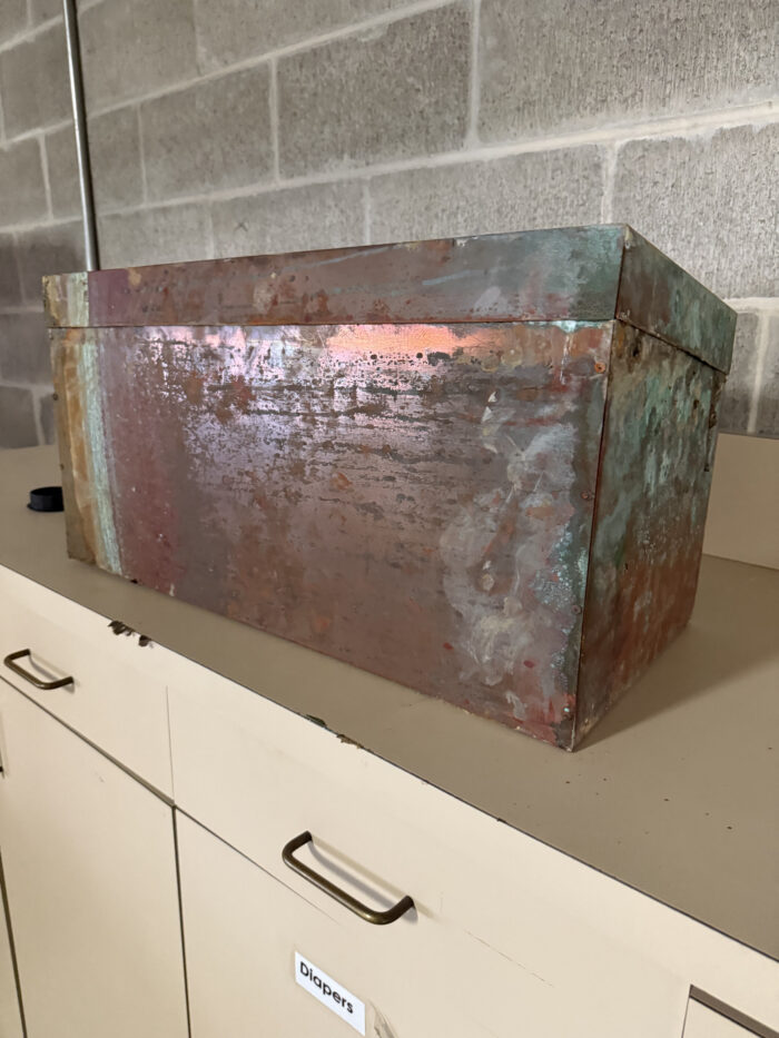 July 25 - The time capsule is a copper-colored box that has considerable rust and patina after several decades in the PVC pipe.